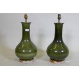A pair of green glazed ceramic table lamps with brass mounts, mounted on distressed giltwood
