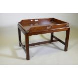 An antique mahogany butler's tray with brass mounts and shaped end gallery, raised on a later