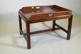 An antique mahogany butler's tray with brass mounts and shaped end gallery, raised on a later