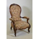 A Victorian walnut spoon back show frame arm chair, with carved decoration and scroll arms, raised