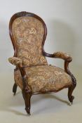 A Victorian walnut spoon back show frame arm chair, with carved decoration and scroll arms, raised