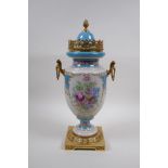 A Sevres style continental porcelain urn with brass mounts, handles and base, with floral bouquet