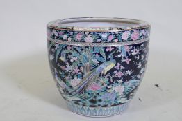 An antique Chinese famille noire ceramic jardiniere, decorated with exotic birds and flowers, 33cm