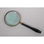 A large brass and ebonised wood magnifying glass, 38cm long, 15cm diameter