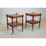 A pair of small yew wood two tier lamp tables, raised on turned columns with brass castors, 32 x