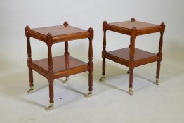A pair of small yew wood two tier lamp tables, raised on turned columns with brass castors, 32 x