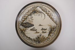 A Chinese Cizhou kiln charger decorated with waterfowl upon a lotus flower pond, character