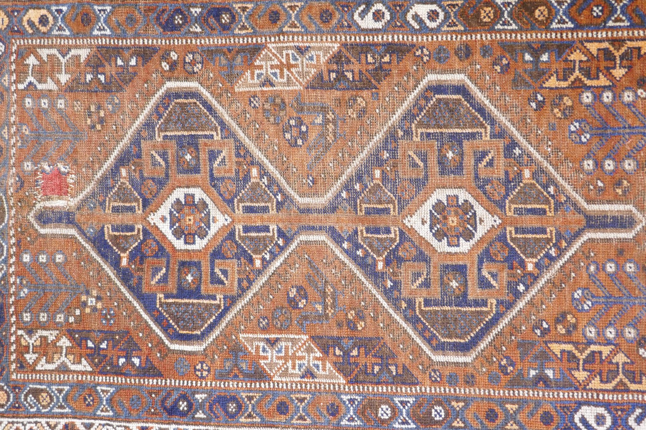 An antique terracotta ground Persian wool village rug, with a twin geometric medallion design, AF, - Image 2 of 5