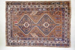 An antique terracotta ground Persian wool village rug, with a twin geometric medallion design, AF,