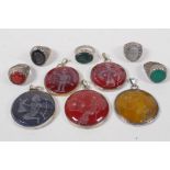 Five Middle Eastern intaglio stone pendants carved with traditional archaic designs in white metal
