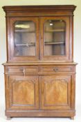A C19th continental walnut bookcase, the upper section with two shaped glazed doors, the base with