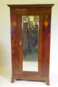 A Victorian inlaid mahogany single door wardrobe with bevelled glass mirror, raised on swept