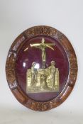 A brass plaque depicting the Pieta, housed in carved oak frame with convex glass, 51cm high