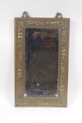 An Arts and Crafts brass wall mirror with repousse fruit and flower decoration, 23 x 38cm
