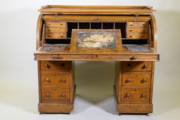 A Victorian mahogany roll top pedestal desk, the upper section fitted with drawers and pigeon