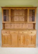 A pine dresser, the upper section with two glazed door flanking open shelves, the base with four