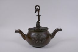 A solid bronze double spouted hanging tea pot with heraldic decoration, 29cm long