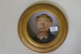 A C19th cold painted and gilt commemorative plaque depicting a bust portrait of Charles Dickens,