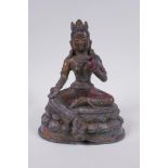 A Sino Tibetan bronze figure of a female deity seated on a lotus throne, with the remnants of gilt