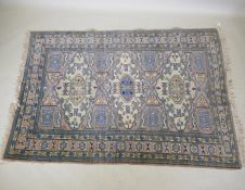 An antique Persian faded pink ground wool carpet with a green geometric medallion design, 140 x