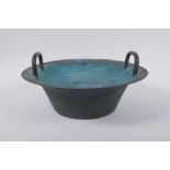 An antique Chinese bronze two handled spouting bowl with dragon decoration, 30cm diameter