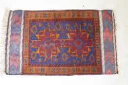 An antique Persian wool rug with a twin red and orange medallion design on a blue field, 82 x 132cm