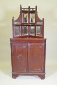 A Victorian mahogany standing corner cabinet with mirrored back and galleried shelves over two