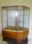 A mid century illuminated mahogany shop display cabinet with two glass shelves, glass top and
