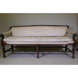 A C19th Anglo-Indian hardwood settee, with carved gadrooned back and scroll arms, raised on