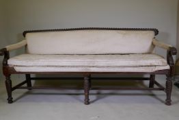A C19th Anglo-Indian hardwood settee, with carved gadrooned back and scroll arms, raised on