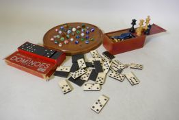 An antique solitaire board with marbles and wood chess set, bone and ebony dominoes and another set