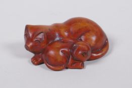 A Japanese carved boxwood netsuke in the form of two cats, signed to base, 6cm wide