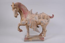A Chinese Tang style pottery model of a caparisoned horse, with the remnants of polychrome paint,