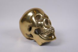 A decorative cast gilt metal skull, 14 cm high