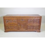 A carved oak sideboard/buffet with five drawers and a single door, with brass swan neck handles,