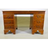 A yew wood five drawer pedestal desk with leather inset top, raised on bracket supports, 122 x 61