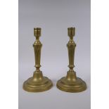 A pair of antique brass column candlesticks, 25cm high