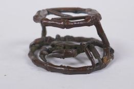 An oriental bronze bamboo style stand with a crab, 6cm diameter
