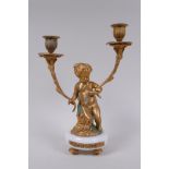 A gilt metal two branch candlestick in the form of a putti, 30cm high