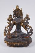 A Sino Tibetan bronze figure of a female deity seated on a lotus throne, with the remnants of gilt