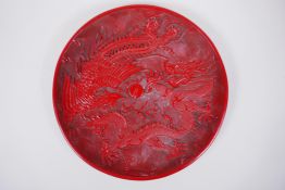 A Chinese cinnabar lacquer style charger with phoenix and dragon decoration, character inscription