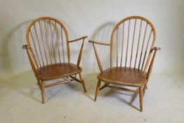 A pair of mid century Ercol beechwood hoopback elbow chairs with solid seats, 83cm