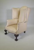 A Georgian style 'Porter's' leather wing back armchair raised on carved ball and claw supports,