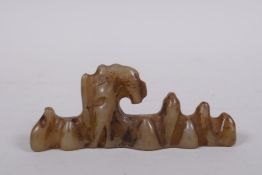 A C19th Chinese celadon jade brush rest carved in the form of a rock formation, 11cm long
