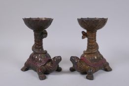 A pair of Chinese gilt and painted bronze pricket candlesticks raised on the backs of tortoises,