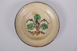 An antique Spanish terracotta dish with a faience glaze and floral decoration, AF repair, 21cm