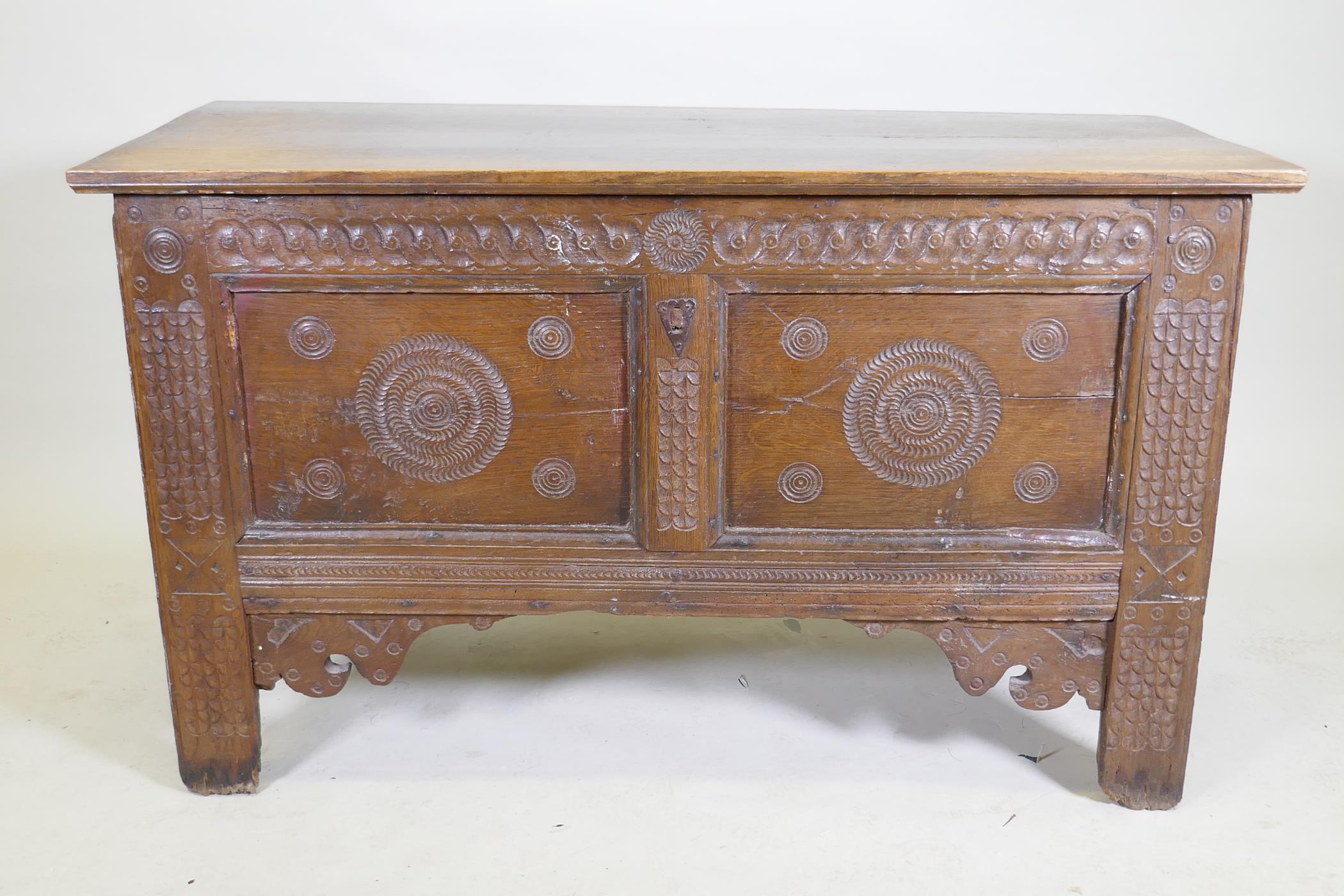 An C18th continental oak coffer, two panelled front with chip carved decoration under a sea scroll