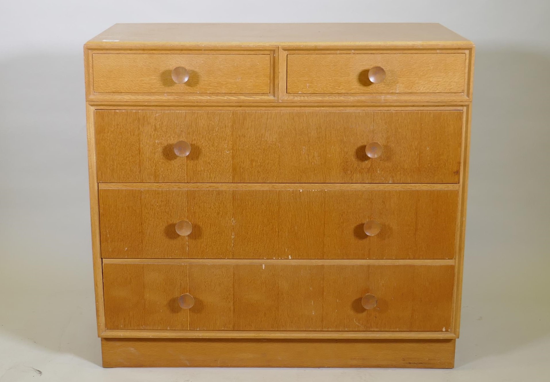 A mid century Meredew oak veneered chest of two over three drawers, raised on a plinth base, AF some