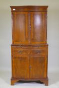 A serpentine front yew wood cocktail cabinet, with two cupboards and mirror back interior,