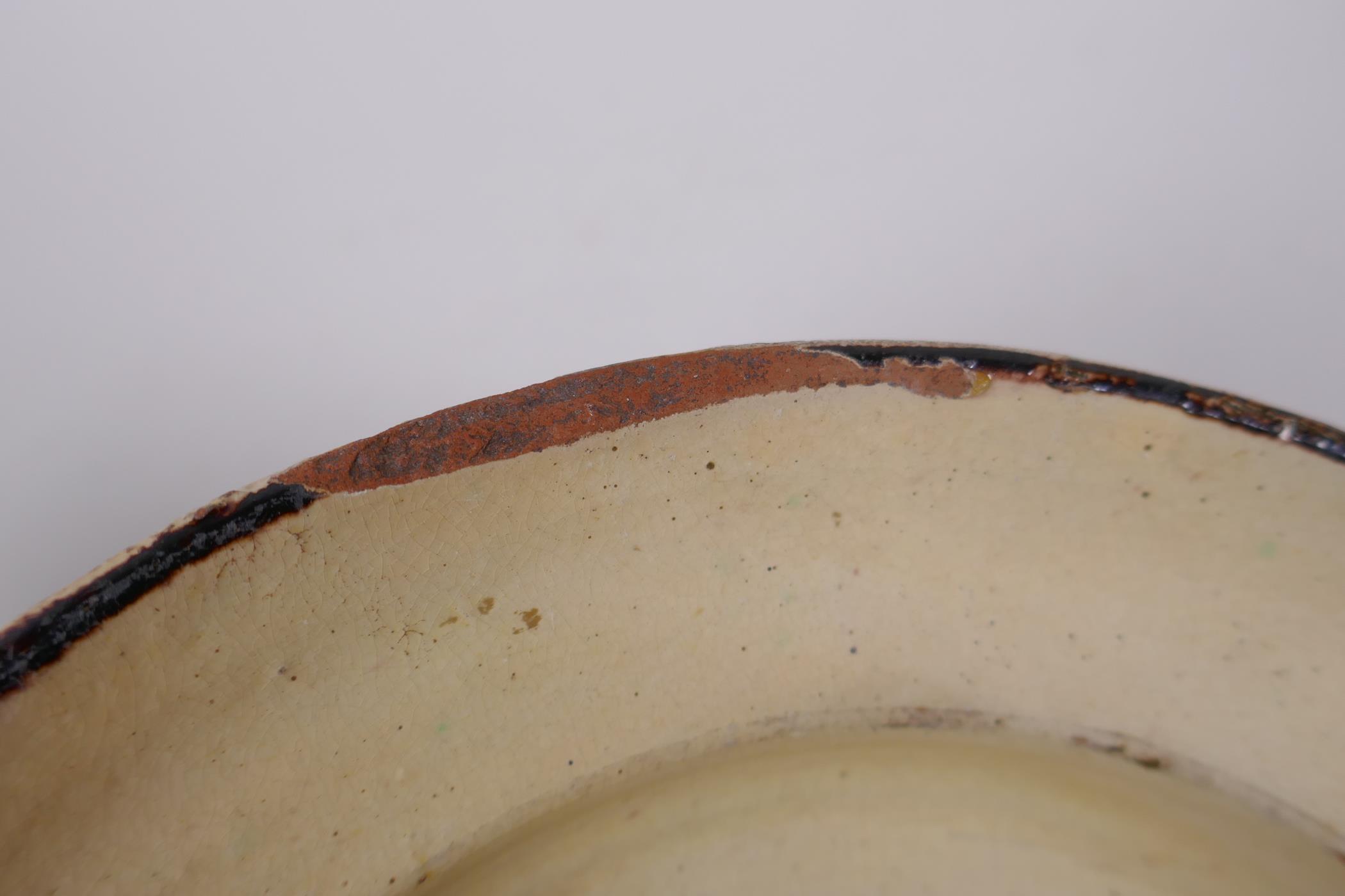 An antique Spanish terracotta dish with a faience glaze and floral decoration, AF repair, 21cm - Image 6 of 6